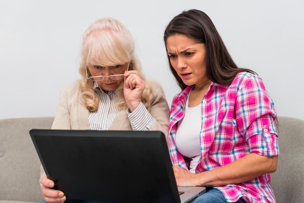 Mother and her adult daughter looking at laptop with curiosity