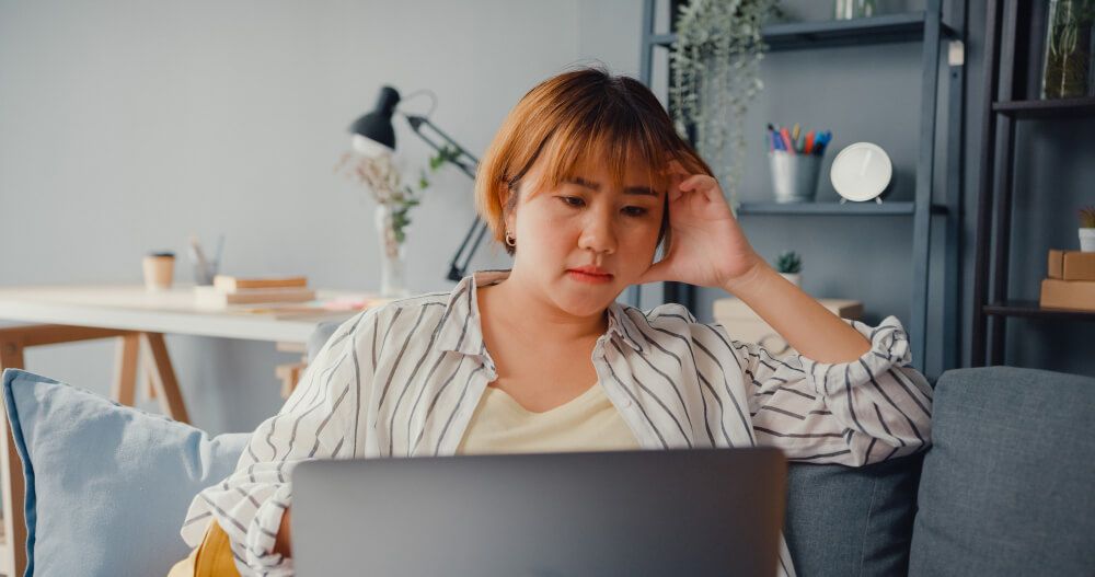 lady feel headache while sitting on couch with laptop online
